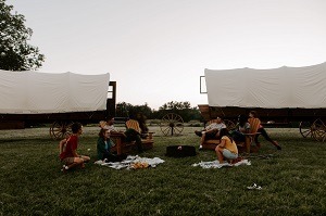 A picture of two PlainsCraft covered wagons with families in front of them.