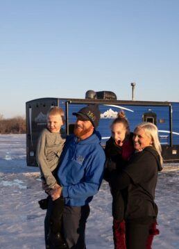 A picture of the Salzburn family next to their Ice Fish House