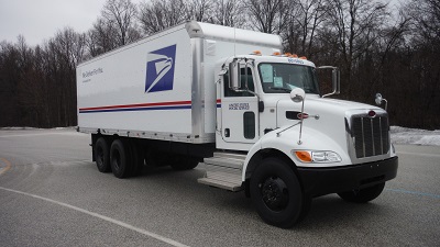 A picture of the US Postal Service truck built on a Utilimaster chassis made by The Shyft Group