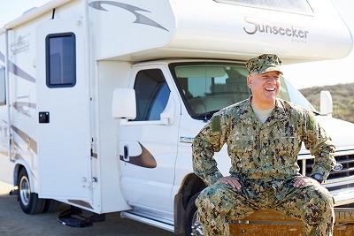 A picture of a veteran in camoflauge sitting in front of an Outdoorsy rental RV