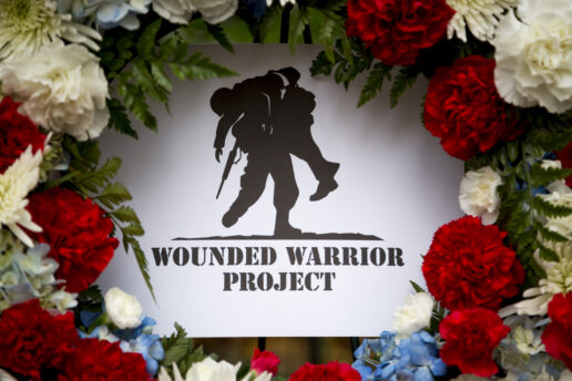 A picture of the Wounded Warrior Project logo surrounded by roses and other foliage as part of a memorial.