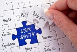 A picture of a Work Safety and Safety First Puzzle with a hand holding the last piece to the puzzle