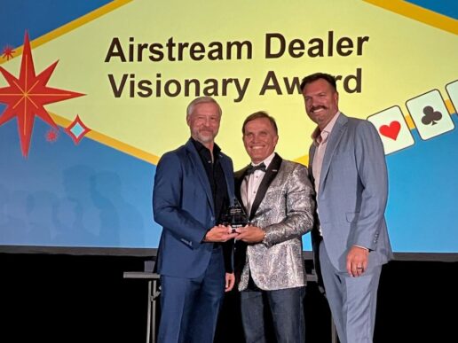 A picture of Airstream President and CEO Bob Wheeler (L) and Airstream Vice President of Sales Bryan Melton (R) presenting the Airstream Dealer Visionary Award to former Airstream Adventures Ted Davis (C) at Caesar's Palace in Las Vegas.