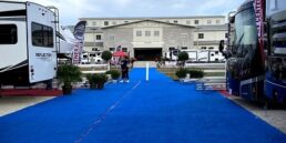 A file picture of the Jacksonville RV MegaShow showing RVs on either side of an aisle with a blue carpet laid across the aisle.