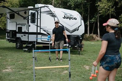 A picture of a couple playing a game outside in front of a Jayco travel trailer