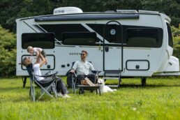 A picture of a family camping with Grand Design's Serenova travel trailer.