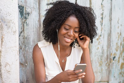 A picture of a young woman happily listening to something on her phone as a metaphor for mindful media