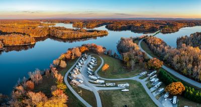 A picture of RVs in a campground by a lake in Tennessee in the autumn with russet colored reeds surrounding the lake