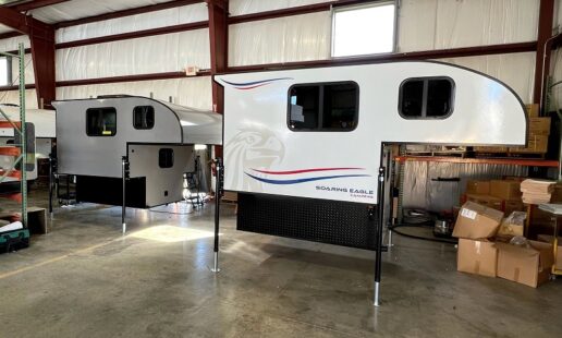 A picture of two Soaring Eagle truck campers on stands in a warehouse.