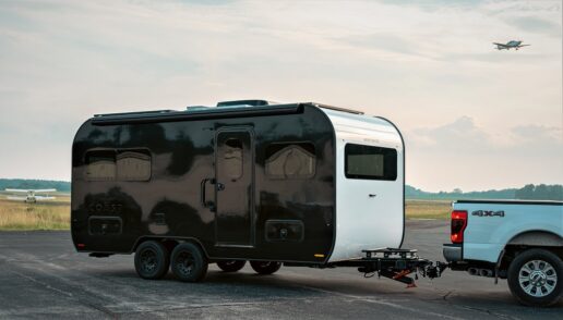 A picture of the Coast 2023 all-electric travel trailer being towed by a pickup.