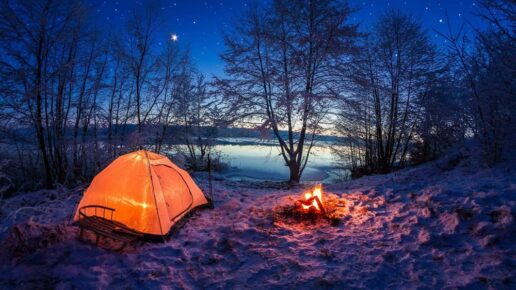 A picture of a tent and a fire in the winter.