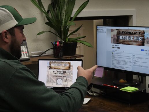 A picture of a man pointing at a screen with the Torklift Trading Post on it.