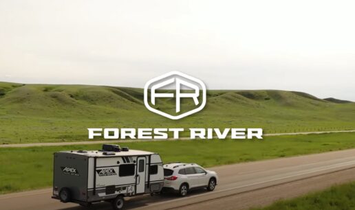 A picture of a screenshot of a vehicle towing a travel trailer with the Forest River logo on the middle of the screen.