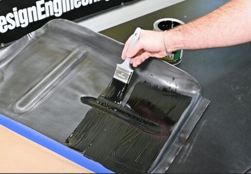 A picture of a brush applying Design Engineering's Boom Mat Liquid Brush On material onto a surface.